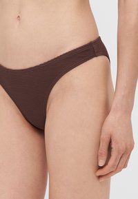 Rjava rebrasta bikinka spodnji del z nizkim pasom in tankimi stranmi, s textured tkanino in brezšivnim zaključkom.