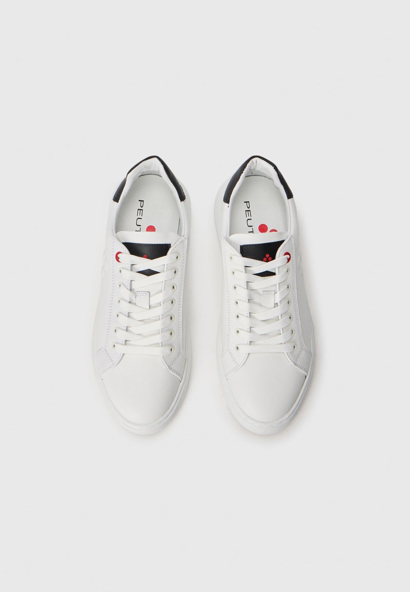 Sneakers bianchi in pelle con una finitura liscia. Presentano dettagli neri sul tallone e un logo rosso. Design classico con lacci.