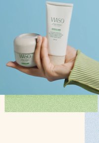 Deux produits de soin WASO de Shiseido : un pot rond vert clair avec un couvercle lisse et un tube haut blanc avec du texte vert et un capuchon texturé.