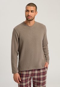 Lichtbruine, lange mouwen, V-hals trui in een zachte textuur, gecombineerd met een geruite broek in marmer, beige en blauwe tinten.