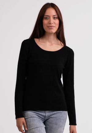 Pull noir à manches longues au fit décontracté, avec un col rond et une texture douce, associé à un jean en denim bleu clair.