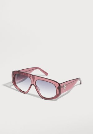 Lunettes de soleil rectangulaires surdimensionnées avec montures roses translucides et verres dégradés gris sur une surface blanche.