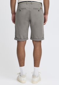 Shorts en coton gris avec des ourlets retroussés, dotés de poches arrière avec fermetures à bouton et d'un détail de ceinture contrastant.