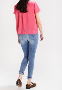 Rosa gerippter Kurzarm-Top, hellblaue Skinny-Jeans mit umgeschlagenen Säumen und braune Ballerinas im Leopardenmuster. Einfaches und lässiges Design.