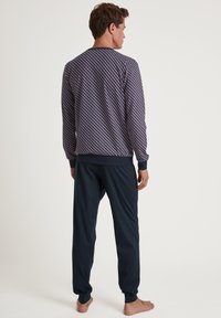 Ensemble de pyjama à motifs marins comprenant un haut à manches longues avec des designs géométriques et un bas élastiqué pour un ajustement confortable.
