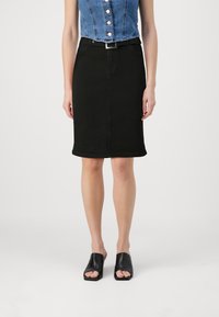 Black denim pencil skirt with a smooth texture, featuring a belt and front side pockets. Paired with black open-toe mules.