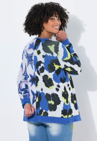 Gebreide trui met een gedurfde print van blauwe, zwarte en neongele luipaardvlekken en sterren; ribgebreide blauwe manchetten en onderrand voegen textuur toe.