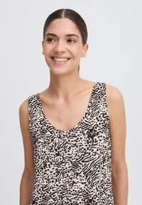 Top fără mâneci dintr-un material ușor, cu un model de imprimeu animalier bej și negru. Decupaj în formă de cerc la gât și design lejer.