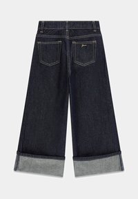 Culotte in denim scuro caratterizzati da gamba larga, orli arrotolati in denim più chiaro, due tasche posteriori e cuciture dorate lungo le cuciture.