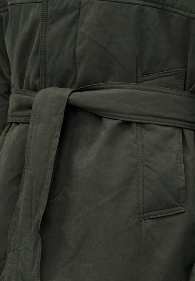 Palton din țesătură verde închis, detaliat cu o curea lată legată în jurul taliei și cu un buzunar cusut vizibil cu clapă.