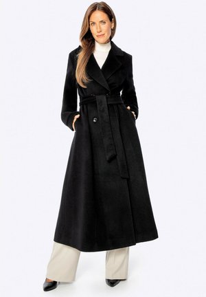 Cappotto di lana nera con design su misura, colletto a revers, maniche lunghe e vita con cintura. Presenta due tasche e un taglio lungo.