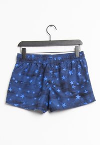 Shorts de bain bleus avec un motif d'étoiles, dotés d'une ceinture élastique et d'un tissu léger et lisse. Suspendus à un crochet noir.