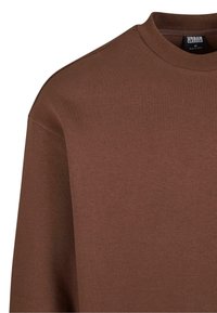 Sudadera marrón con cuello redondo, mangas largas y una textura suave. Incluye una etiqueta con el nombre de la marca "Urban Classics" visible.