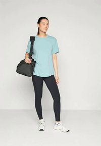 Heledat sinine lühikeste varrukatega T-särk, tumesinised retuusid, must õlakott ja valged tennisetossud. Lihtne, juhuslik disain, mis on mugava lõikega.