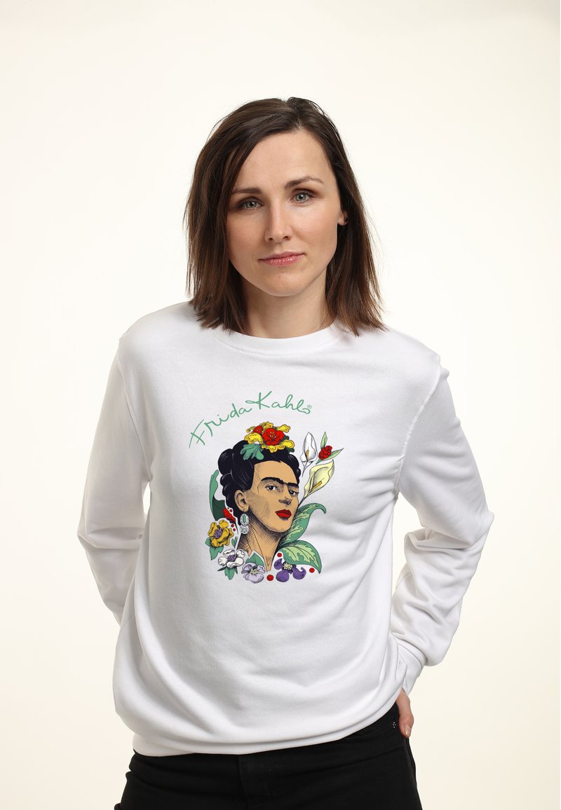 Hvid sweatshirt med en farverig illustration af Frida Kahlo omgivet af blomster og blade. Designet inkluderer blomsteragtige accenter og tekst.