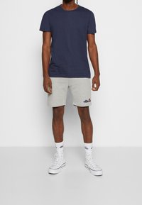 T-shirt en coton marine, short en coton gris avec logo, baskets montantes blanches et chaussettes blanches avec logo. Design simple et coupe décontractée.