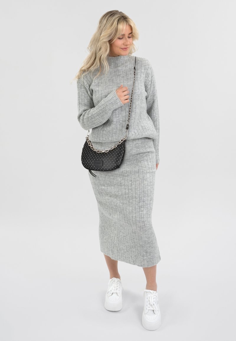 Conjunto de suéter de punto acanalado gris y falda midi, combinado con zapatillas blancas y un bolso negro de lunares con una correa de cadena.