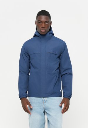 Navy blue waterproof jacket with a high collar, adjustable hood, zip and flap pockets, elastic cuffs, and a logo on the left chest.