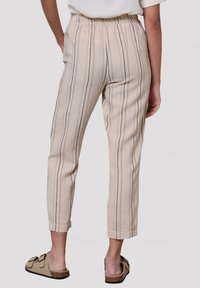 Ljust beige, randiga byxor med elastisk midja och avsmalnande ben. Tillverkade av textil med struktur, med subtila svarta linjer och sidofickor.