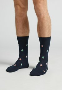 Calcetines azul marino con una mezcla de algodón que presentan coloridos patrones de hongos en verde y rojo, terminados con una puntera reforzada y una textura suave.