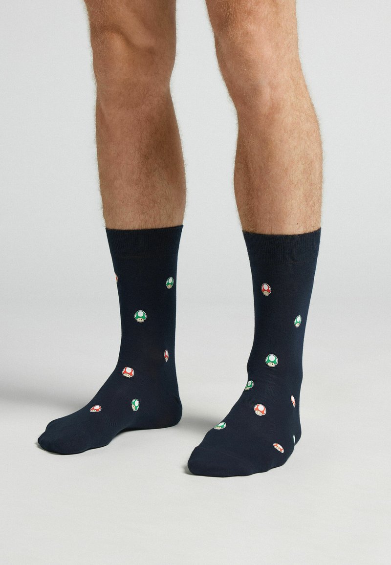 Calcetines azul marino con una mezcla de algodón que presentan coloridos patrones de hongos en verde y rojo, terminados con una puntera reforzada y una textura suave.