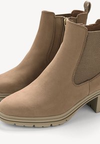 Bottes à la cheville marron avec un dessus en cuir lisse, des bandes élastiques sur les côtés et une semelle en caoutchouc texturée avec un petit talon carré.