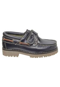 Zapato slip-on de cuero azul marino con una correa de velcro, suela de goma con ranuras de tracción, y costuras y acentos en contraste en color marrón claro.