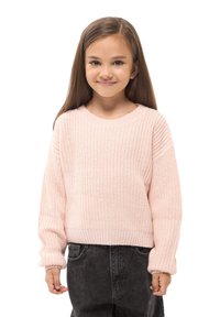 Jasnoróżowy sweter dziany z okrągłym dekoltem, opuszczonymi ramionami i ściągaczami. Nosi się go na ciemnoszarych, wysokich spodniach.