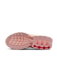 Suela de zapatilla deportiva rosa con una superficie de goma texturizada, patrones de agarre prominentes y acentos circulares rojos cerca del talón.