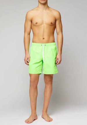 Costumi da bagno verde neon realizzati in tessuto leggero. Presentano una cintura elastica con un cordino bianco e un design semplice e privo di decorazioni.