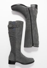 Stivali alti in suede grigio con chiusura laterale a zip e dettaglio con fibbia. Presentano un tacco a blocco e cuciture a contrasto lungo le cuciture.