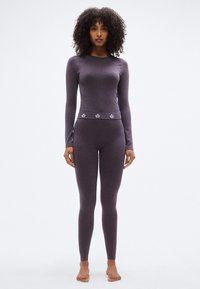 Μακρυμάνικο μωβ θερμικό τοπ και εφαρμοστά κολάν, κατασκευασμένα από απαλό ύφασμα με διακριτική υφή heather και διακοσμητικές λεπτομέρειες στη μέση.