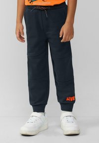 Marineblaue Jogginghose aus weichem Stoff mit einem Kordelzugbund. Verfügt über Nähte an den Knien und ein oranges "SLVR"-Logo am Bein.
