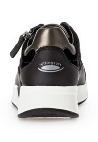 Sneaker nera con parte superiore testurizzata, dettagli metallici e suola bianca. Presenta una cerniera laterale e il marchio "rollingsoft" sul tallone.