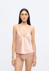 Satiinist kampsun ja sobivad lühikesed püksid pehmes roosas toonis, millel on geomeetriline pitsikaarte ja peened spagetirihmad. Sile ja kerge tekstuur.