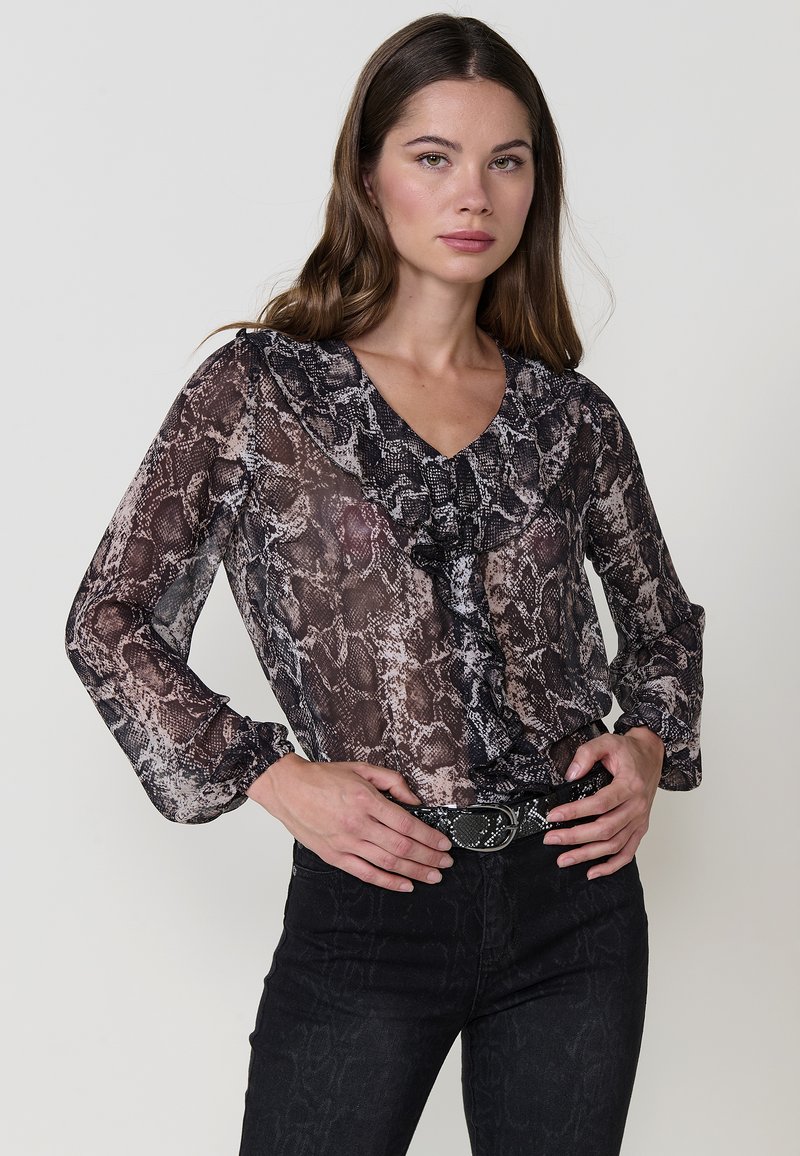 Blusa trasparente a maniche lunghe con motivo a stampa serpente in tonalità di nero e beige. Presenta un scollo a V con volant e maniche ampie.
