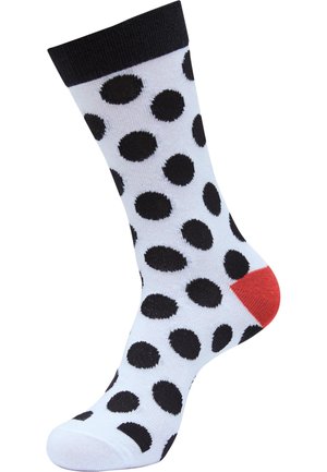 Schwarz-weiße Punktesocken mit rotem Fersenbereich. Die Socke hat eine glatte Textur und einen gerippten schwarzen Bündchen oben.