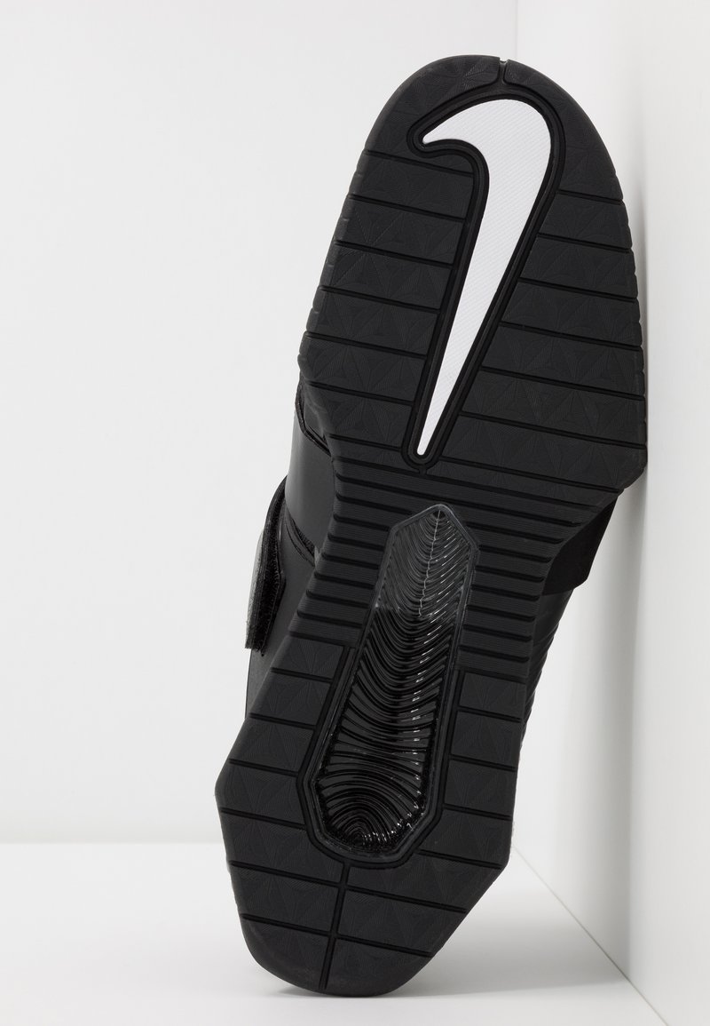 Czarna sportowa podeszwa buta z teksturowanej gumy, z wyraźnym białym logo Nike i elastycznym, żebrowanym wzorem zapewniającym przyczepność.