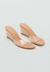 Nude wedge sandals with a braided straw heel, clear plastic straps, and a smooth footbed. Designed for slip-on wear.