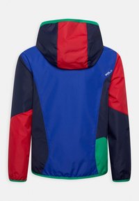 Kurtka w blokowe kolory z panelami w odcieniach niebieskiego, czerwonego, zielonego i granatowego. Gładki materiał z kapturem i elastycznymi mankietami. Logo "Polo" na ramieniu.