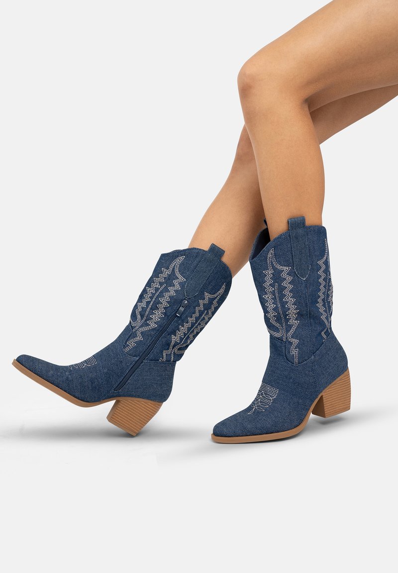 Botas de vaquero de denim con punteras puntiagudas, intrincadas costuras blancas, un tacón bajo y tiradores para facilitar el uso.