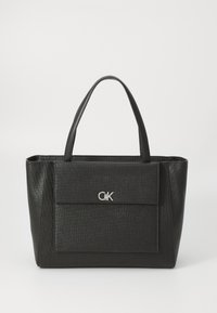 Black tote bag with a textured finish, featuring two sturdy handles and a front flap pocket, adorned with a silver logo accent.