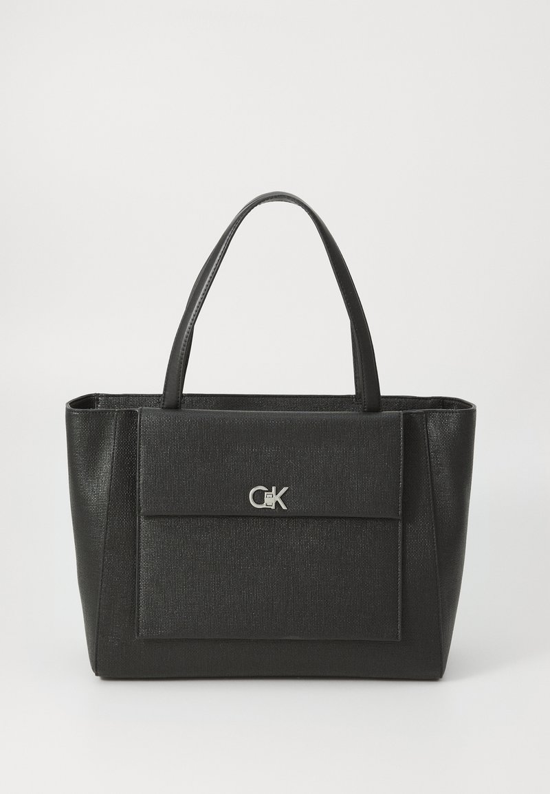 Black tote bag with a textured finish, featuring two sturdy handles and a front flap pocket, adorned with a silver logo accent.