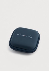 Compact, marineblauw hardcase-etui met ritssluiting; voorzien van het "TOMMY HILFIGER"-logo in reliëf aan de voorkant; gladde textuur.