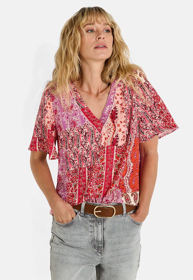 Blouse à manches courtes avec des motifs floraux et paisley multicolores, dotée d'un décolleté en V et d'une coupe décontractée. Fabriquée en tissu léger.