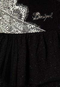 Schwarzes Kleid mit Spitzenverzierungen in floralem Muster und Rüschentextur. Enthält gestickte Akzente des Markennamens.