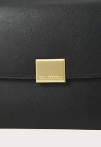 Clutch in pelle nera con superficie testurizzata e chiusura magnetica in metallo dorato. Presenta un logo impresso sulla chiusura, design minimalista.