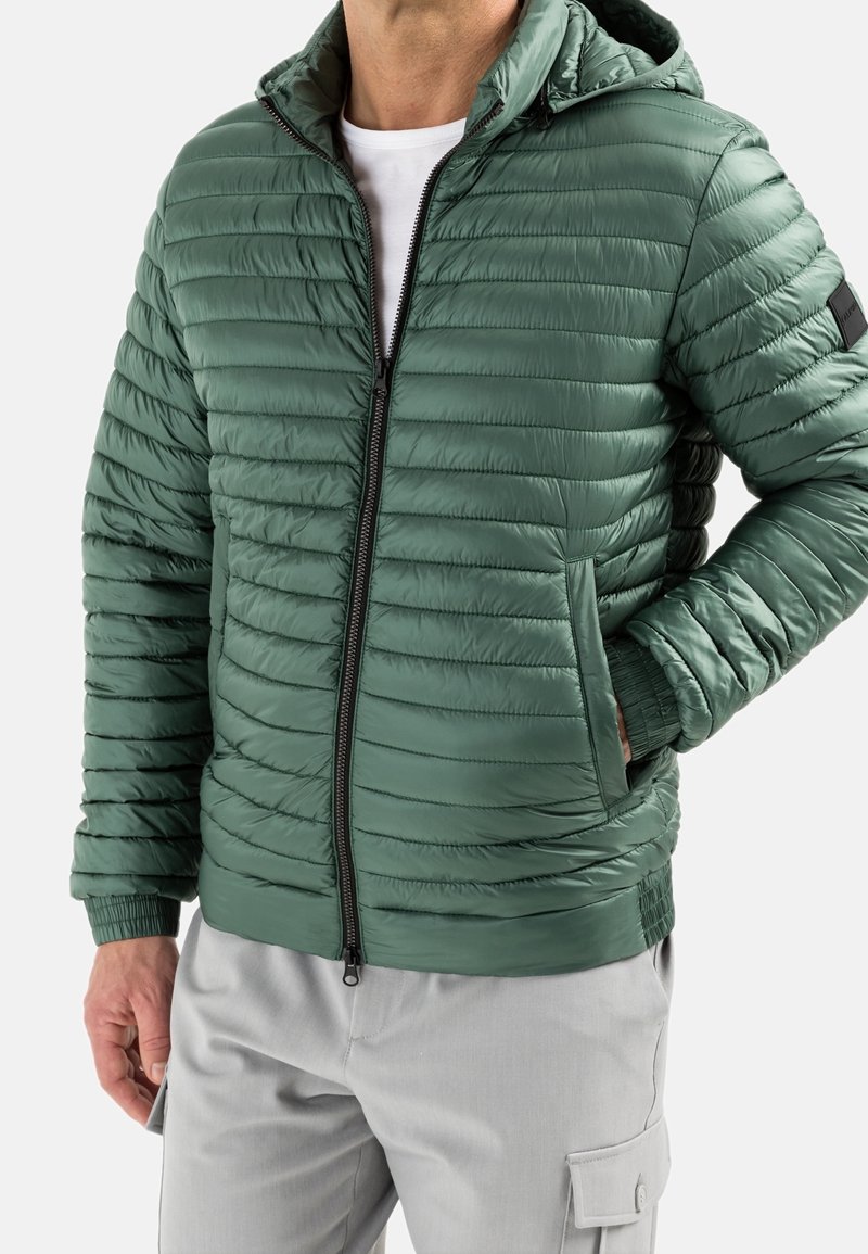 Green puffer jacket with a hood, featuring a quilted design, front zipper, and side pockets. Made from a smooth, shiny material.