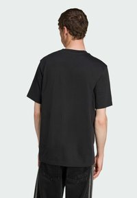 Black cotton t-shirt with short sleeves, a relaxed fit, and a classic crew neckline, featuring a smooth texture and minimalist design.