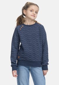 Felpa blu navy con motivo a zigzag e dettagli in legno. Presenta polsini e orlo a coste. Abbinata a jeans azzurri.